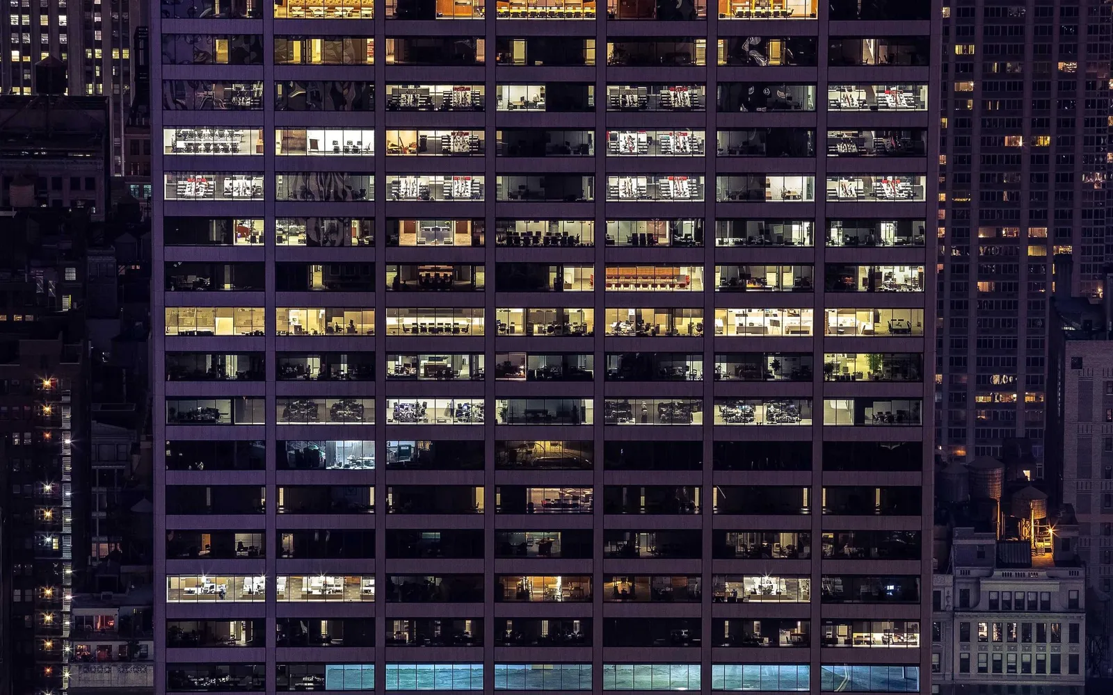 Fachada de um edifício à noite com janelas de escritórios acesas